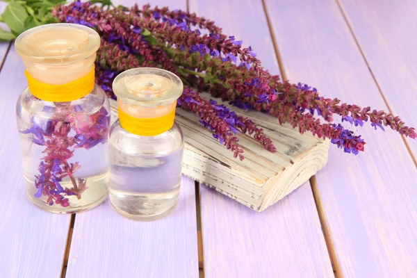 Geneeskundeflessen met salvia bloemen op paarse houten achtergrond — Stockfoto