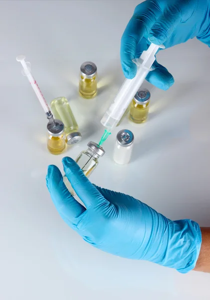 Medical bottles and syringes in hand on gray background — Stock Photo, Image