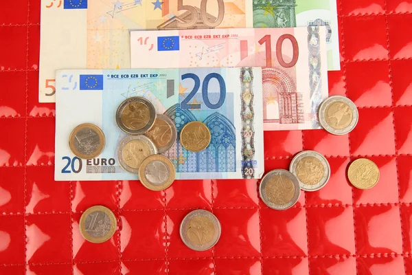 Notas de euro e cêntimos de euro sobre fundo vermelho — Fotografia de Stock