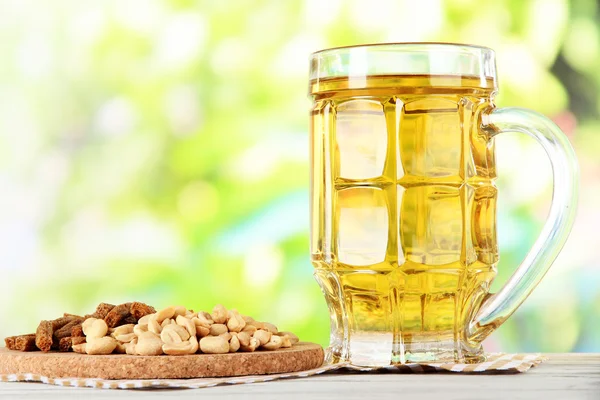 Beer in glass crunches, and nuts on napkin on table on nature background background — Stock Photo, Image