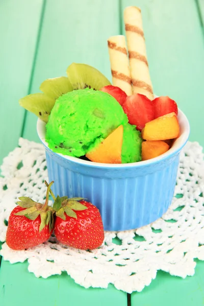 Delicious ice cream with fruits and berries in bowl on wooden table — Stock Photo, Image