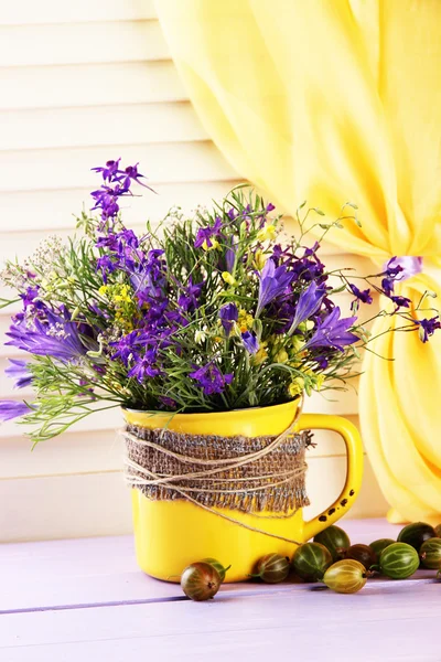 Schöner Strauß Wildblumen in Tasse und Beeren auf Holztisch — Stockfoto