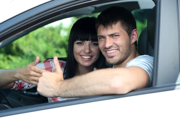 Счастливая молодая пара за рулем автомобиля — стоковое фото