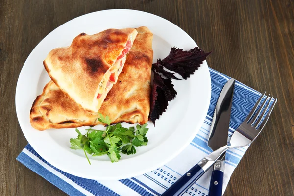 Pizza calzone na štítku na ubrousek na dřevěný stůl — Stock fotografie