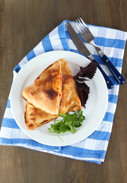 Pizza calzones on plate on napkin on wooden table — Stock Photo, Image