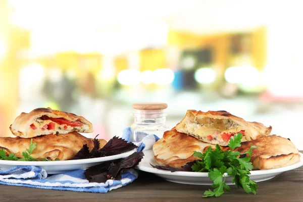 Calzones de pizza sobre platos sobre mesa sobre fondo de habitación —  Fotos de Stock