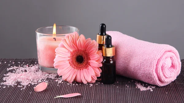 Beautiful pink candle with flower and towel on bamboo mat — Stock Photo, Image