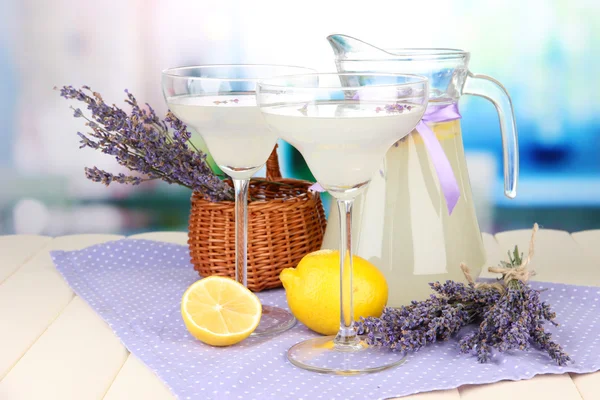 Limonata di lavanda in brocca di vetro e bicchieri da cocktail, su sfondo brillante — Foto Stock