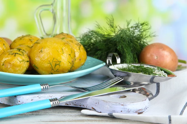 Patatas hervidas en platina sobre tabla de madera cerca de servilleta sobre mesa de madera sobre fondo natural —  Fotos de Stock