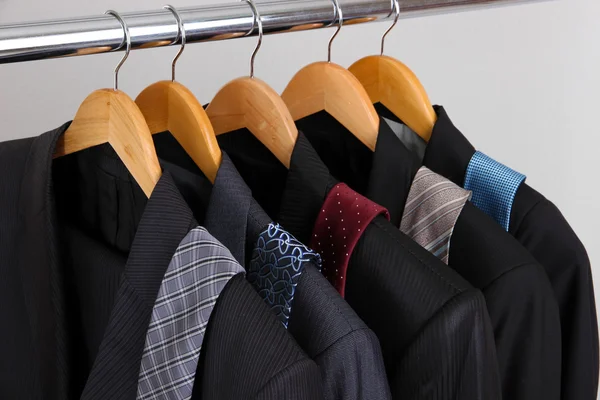 Anzüge und Krawatten auf Kleiderbügeln auf grauem Hintergrund — Stockfoto