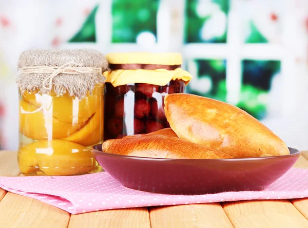 Fresh baked pasties with fruit jam, on wooden table, on bright background — Stock Photo, Image