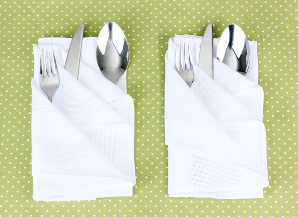 Folded napkin with fork, spoon and knife on color background — Stock Photo, Image