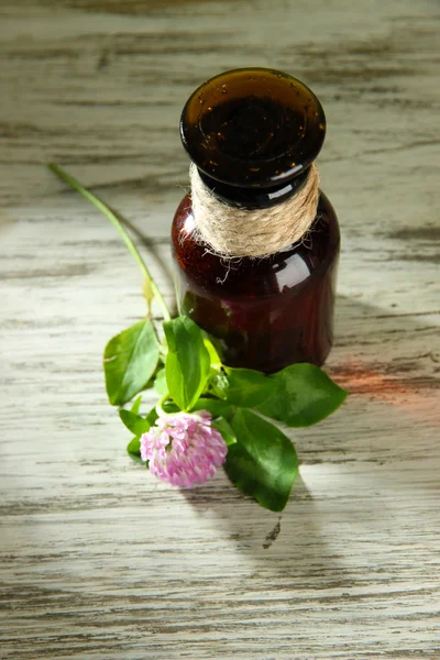 Medicine bottle with clover flower on wooden table — Stock Photo, Image