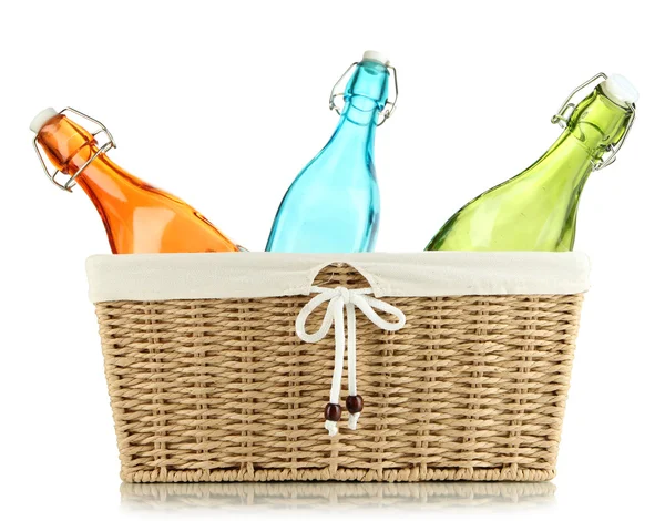 Color glass bottles in wicker basket, isolated on white — Stock Photo, Image