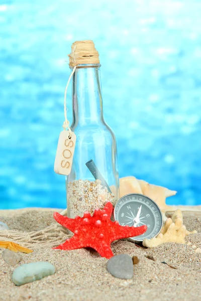 Glazen fles met opmerking binnen op heldere blauwe achtergrond — Stockfoto