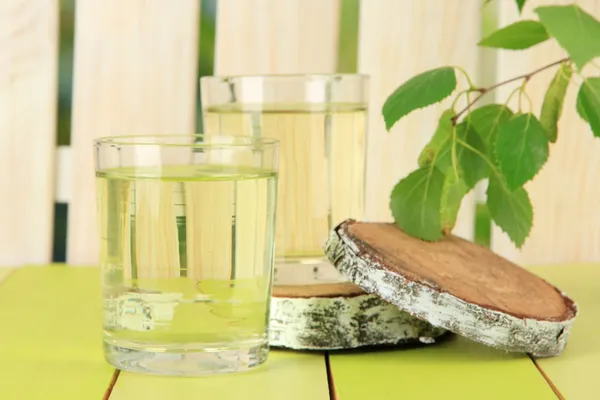 Glasses of birch sap on green wooden table — Stock Image Glasses of birch sap on green wooden table Stock Photo