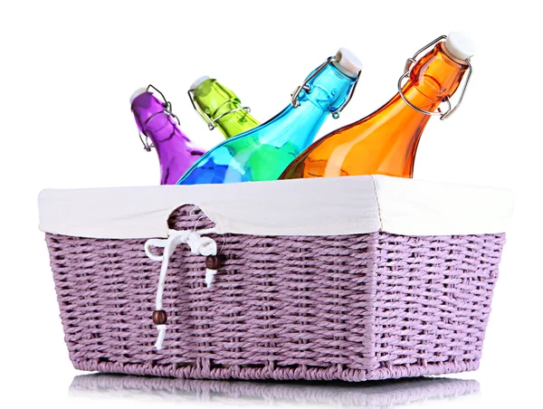 Color glass bottles in wicker basket, isolated on white — Stock Photo, Image