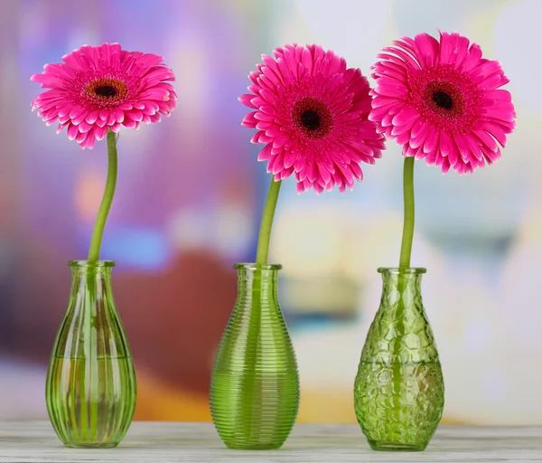 Krásná růžová gerbera květiny ve vázách na dřevěný stůl — Stock fotografie