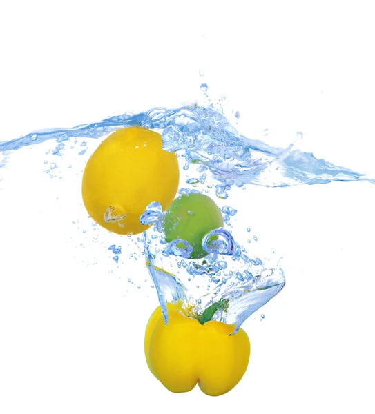 Tropical fruits and vegetables falling into water with splash isolated