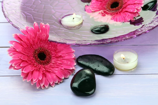 Pierres de spa, belles fleurs de gerbera et bougies sur l'eau — Photo