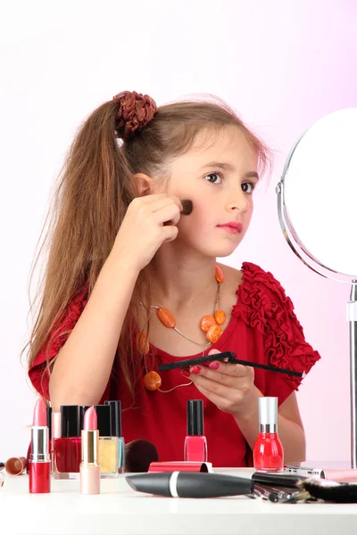 Маленькая девочка в мамином платье, пытается покрасить лицо — стоковое фото
