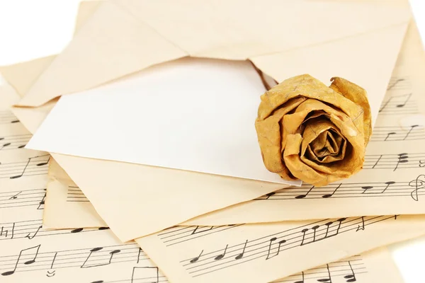 Old envelope with blank paper with dried rose on music sheets close up — Stock Photo, Image