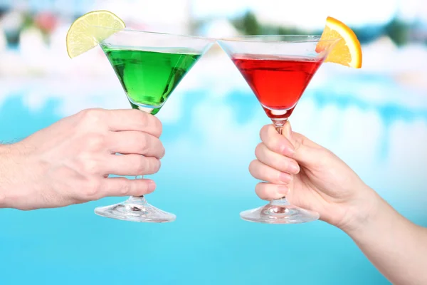 Cocktails in handen van mannen en vrouwen op zwembad achtergrond — Stockfoto