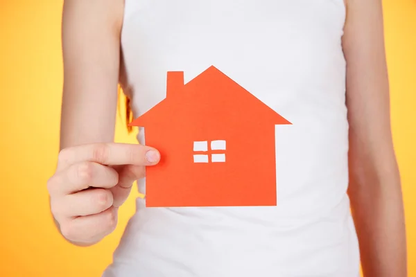 Maison en papier dans les mains sur fond orange — Photo