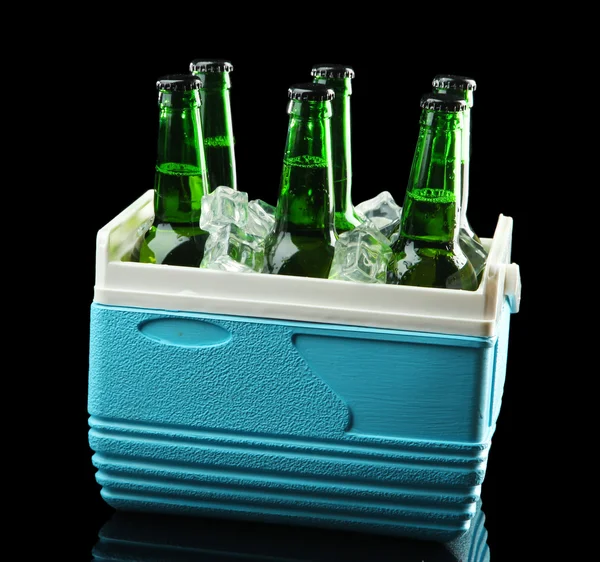 Bottles of beer with ice cubes in mini refrigerator, on black background — Stock Photo, Image