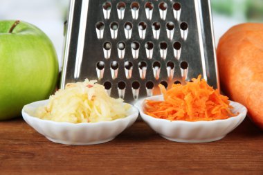 Metal grater and apple, carrot, on bright background clipart