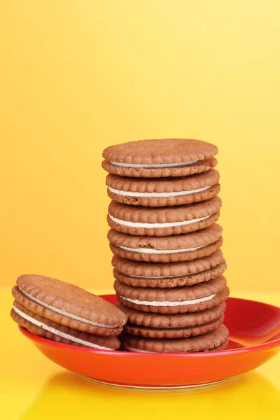 Μπισκότα σοκολάτας με κρεμώδη στρώμα στο κόκκινο πλάκα κίτρινο φόντο — Φωτογραφία Αρχείου