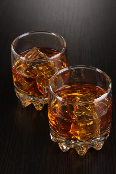 Brandy glasses with ice on wooden background — Stock Photo, Image