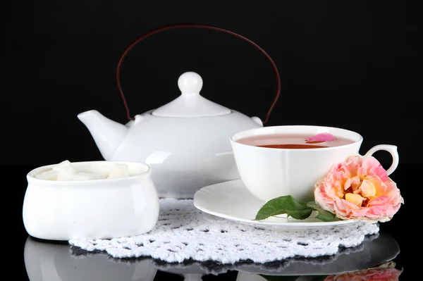 Hervidor de agua y taza de té de rosa de té sobre fondo negro servilleta — Foto de Stock