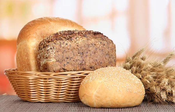 Baked bread in wicker basket on window background — Stock Photo, Image