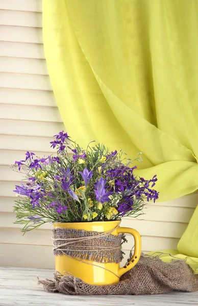 Vacker bukett av blommor i cup på träbord — Stockfoto