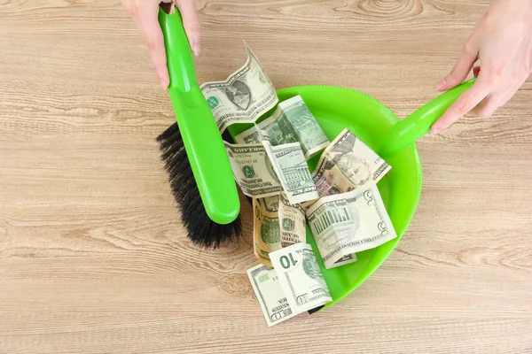 Sweeps money in the shovel on wooden background close-up — Stock Photo, Image