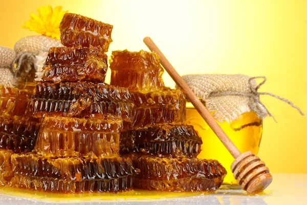 Favos de mel doces e jarra com mel, no fundo amarelo — Fotografia de Stock