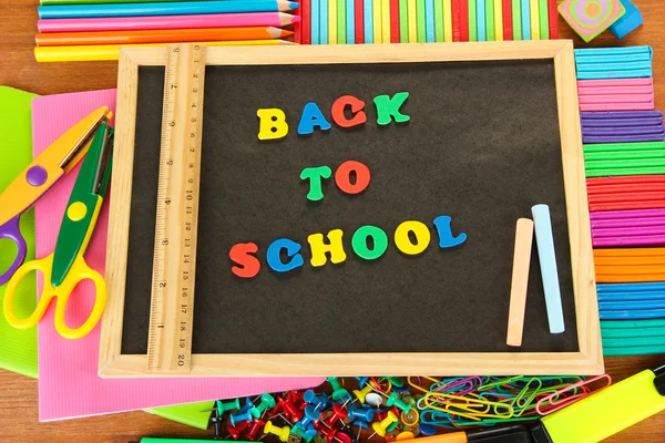 Kleine schoolbord met school levert op houten achtergrond. terug naar school — Stockfoto