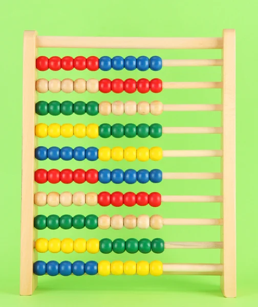 Bright wooden toy abacus, on green background — Stock Photo, Image