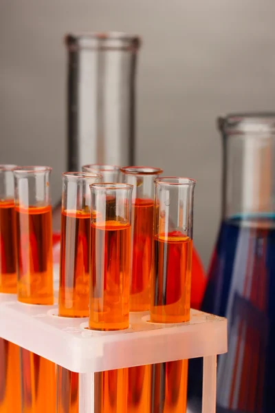 Pipeta de laboratorio con gota de líquido de color sobre tubos de ensayo de vidrio, primer plano — Foto de Stock