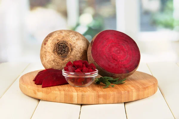 Sliced beetroot on board on wooden table on window background — Stock Photo, Image