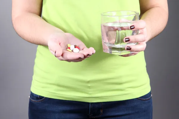 Muchas píldoras y agua de vidrio en la mano —  Fotos de Stock