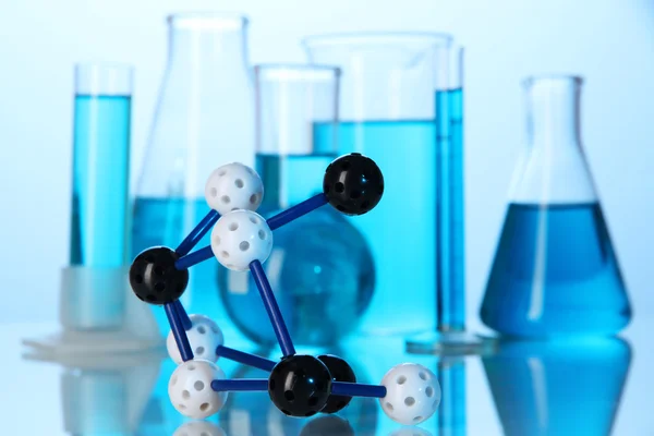 Molécula modelo e tubos de ensaio com líquido sobre fundo azul — Fotografia de Stock
