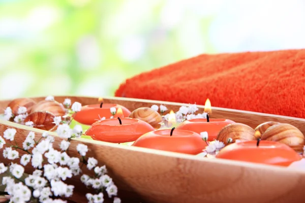 Mooie kaarsen in water op houten tafel op natuurlijke achtergrond — Stockfoto