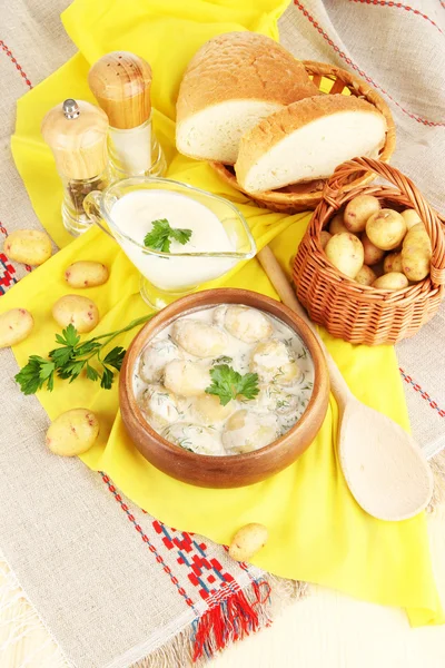 Tender young potatoes with sour cream and herbs in wooden bowl on tablecloth close-up — Stock Photo, Image