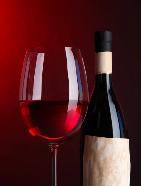 Copa de vino con botella sobre fondo rojo brillante — Foto de Stock