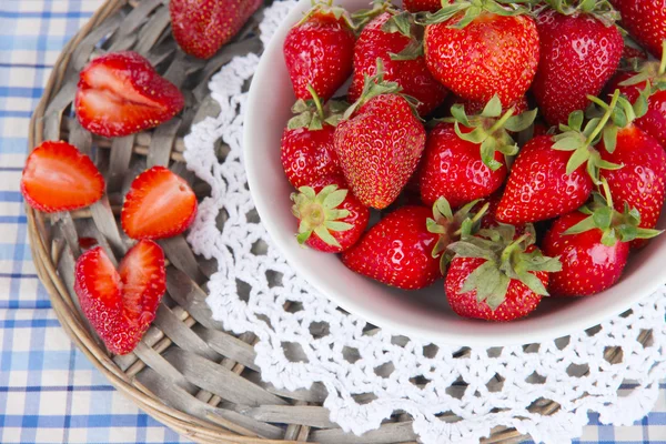 Strawberries in plate on wicker stand on napkin — Stock Photo, Image