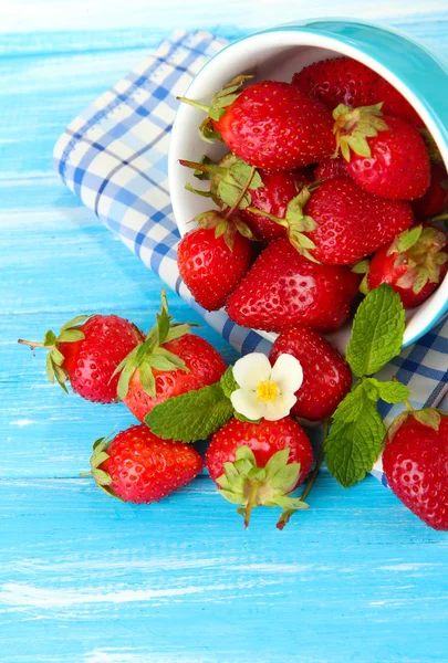 Fresas dulces maduras en taza sobre mesa de madera azul — Foto de Stock