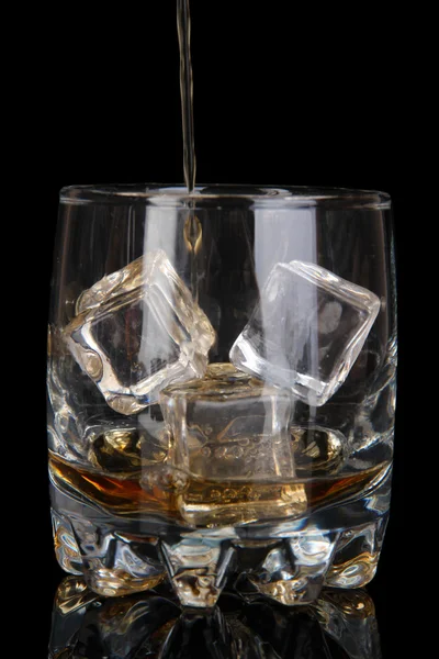 Brandy derramando em vidro no fundo preto — Fotografia de Stock
