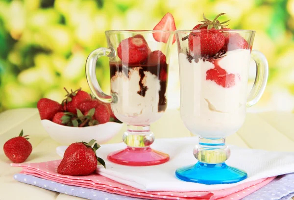 Deliziosi dessert alla fragola in vaso di vetro su tavolo di legno su sfondo naturale — Foto Stock